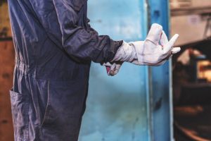 Factory employee putting on protective work gloves before welding