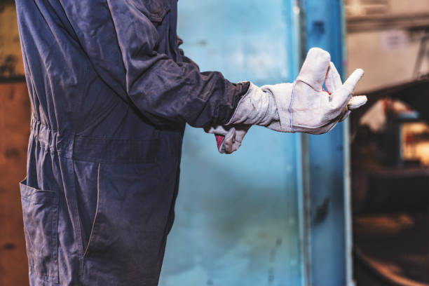 Factory employee putting on protective work gloves before welding